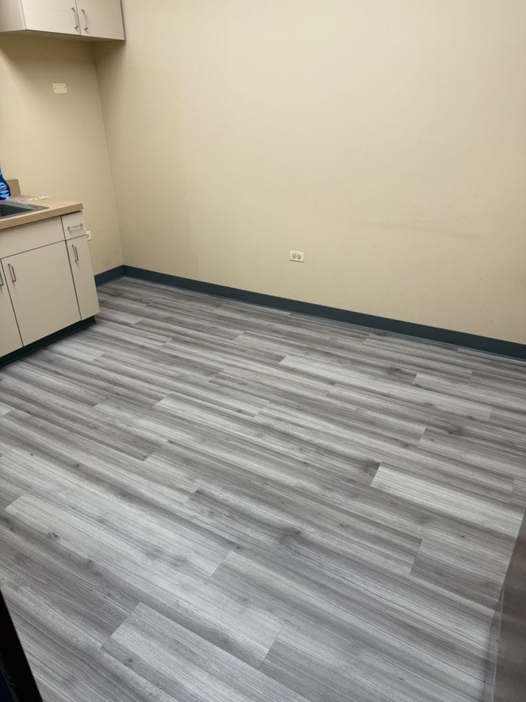 Newly installed gray luxury vinyl plank flooring in office kitchenette at The Oaks in Mokena Illinois